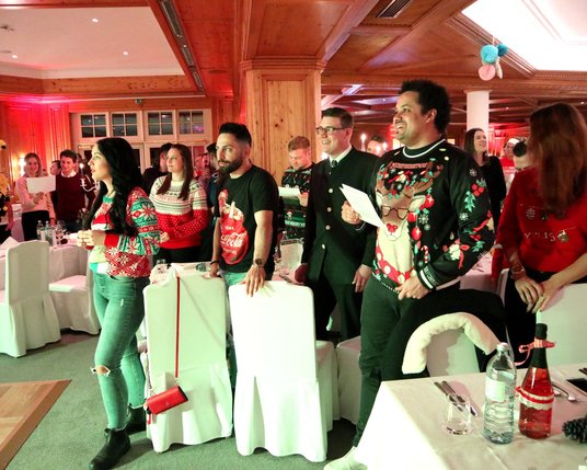 Mitarbeiter:innen auf der Weihnachtsfeier mit Weihnachtspullovern in einem 5-Sterne Hotel