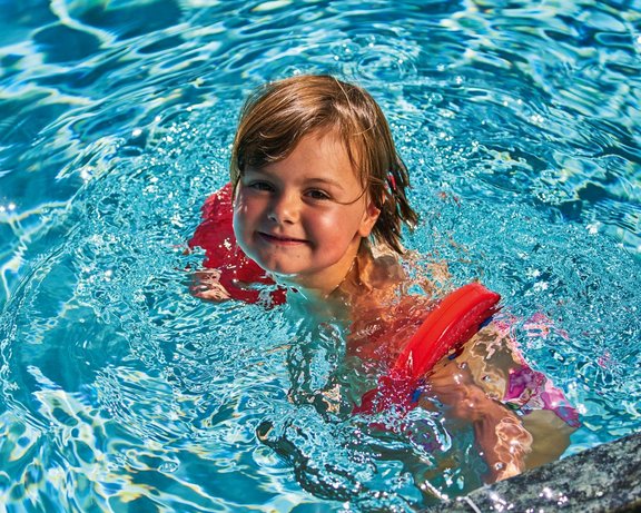 Kind schwimmt im Pool eines Kinderhotels