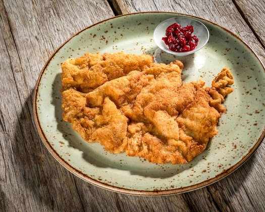 Detailaufnahme eines Wiener Schnitzels mit Preiselbeeren auf einem Teller 