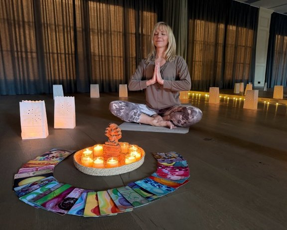 Nehmen Sie an einer entspannenden Yoga-Stunde teil Die Yogalehrerin Chistriane Hosemann bei einer Meditation, umgeben von Kerzen