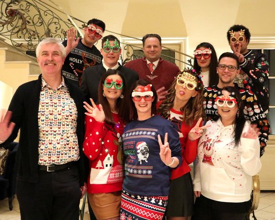 Mitarbeiter:innen auf der Weihnachtsfeier mit Weihnachtspullovern in einem 5-Sterne Hotel