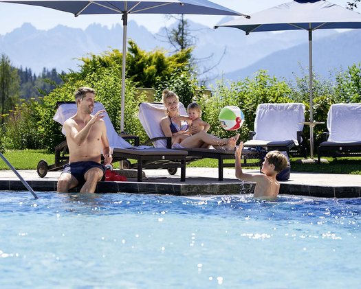 Familienurlaub Eine Familie verbringt die gemeinsame Zeit am Pool im Familienhotel in Tirol