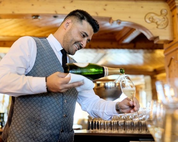 A sparkling start to an exceptional evening of fine dining. A member of the service team pouring champagne at Interalpen Culinarium.