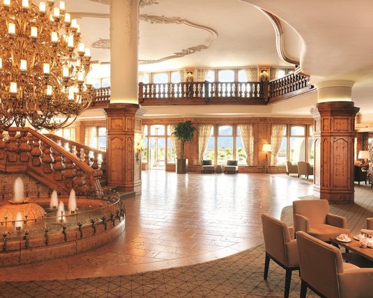 Lobby Interalpen-Hotel Tyrol Einblick in die offen gestaltete Hotelhalle mit großem Kronleuchter