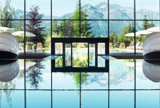 Aufnahme des Indoorpools im lichtdurchfluteten Spa-Bereich mit einzigartigem Blick auf die umliegende Bergwelt