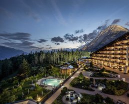 Exterior view of the illuminated Interalpen Leading Hotel in Tyrol on a warm summer night