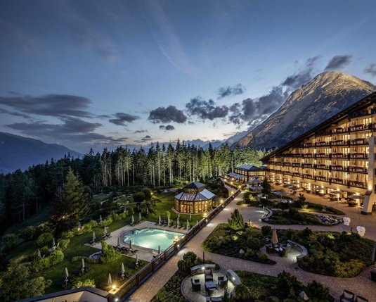 Exterior view of the illuminated Interalpen Leading Hotel in Tyrol on a warm summer night