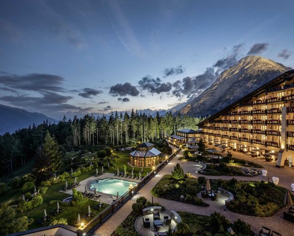 Tagen & Feiern im Interalpen-Hotel Tyrol Außenansicht des beleuchteten Interalpen Leading Hotels in Tirol in einer lauen Sommernacht