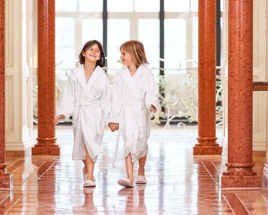 Kids Zwei kleine Kinder in weißen Bademänteln im Wellness-Bereich des Familienhotels in Tirol
