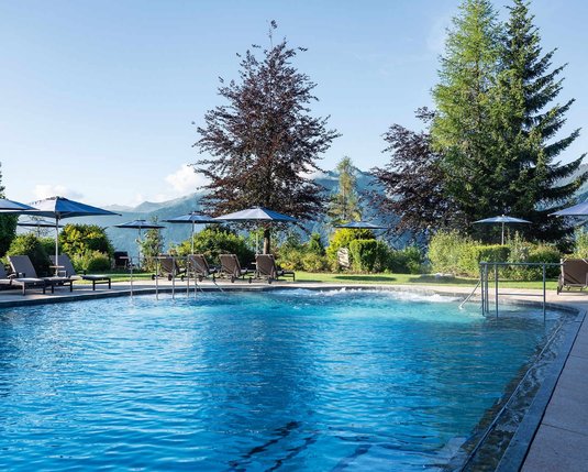 Blick über den Außenpool in den Spa Garten im Sommer