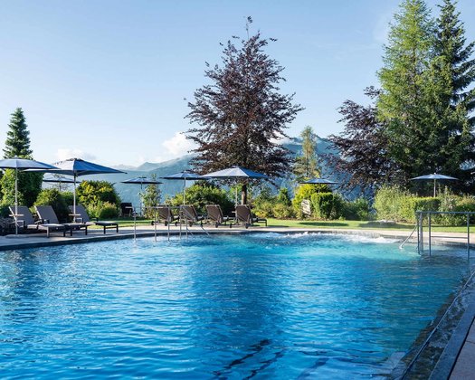 Vom Schwimmkurs bis zur Poolreinigung Blick über den Außenpool in den Spa Garten im Sommer